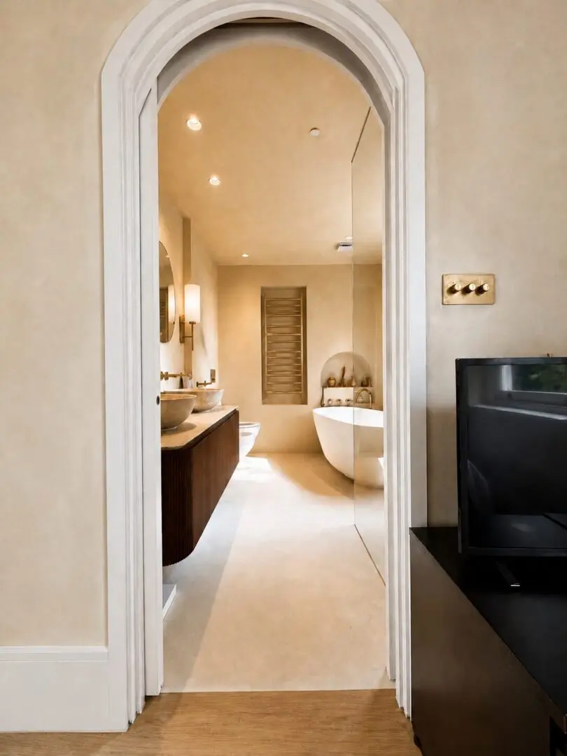 Bathroom with a television sitting on top of a wooden table, two wash basins with taps, a bathtub, a mirror
