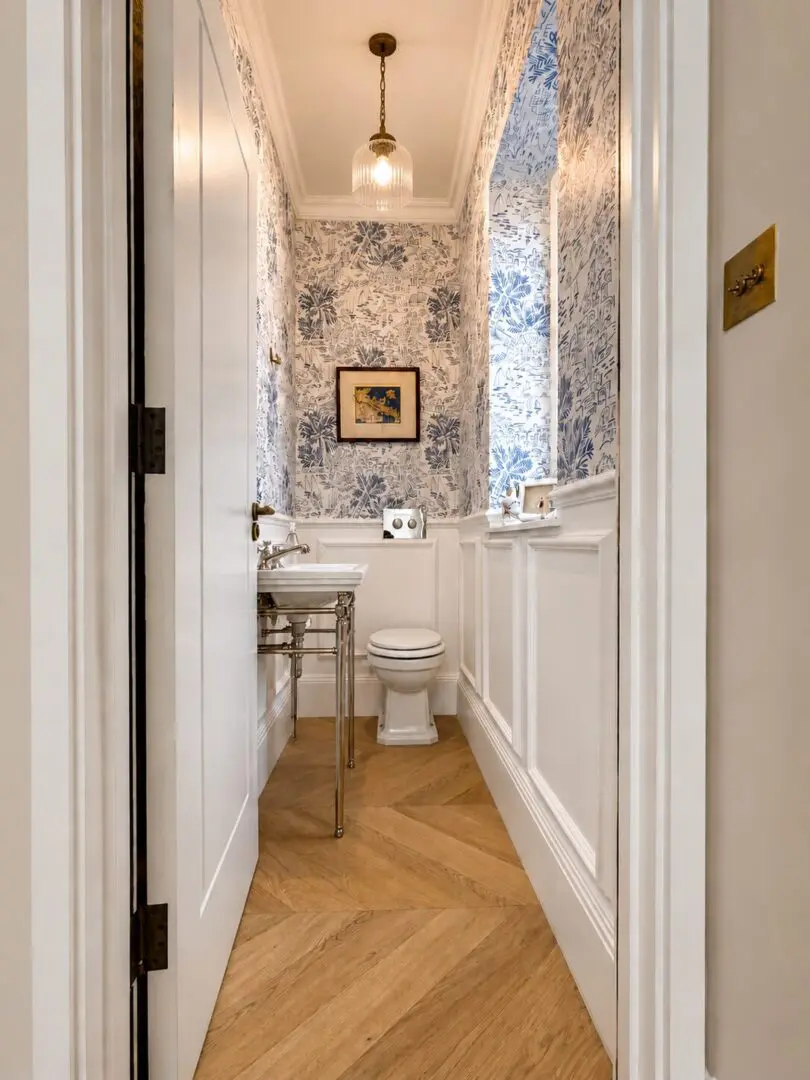 Bathroom with a toilet, sink, mirror, flush tank, wash basin, tap, toilet paper roll, photo frame on the wall, window