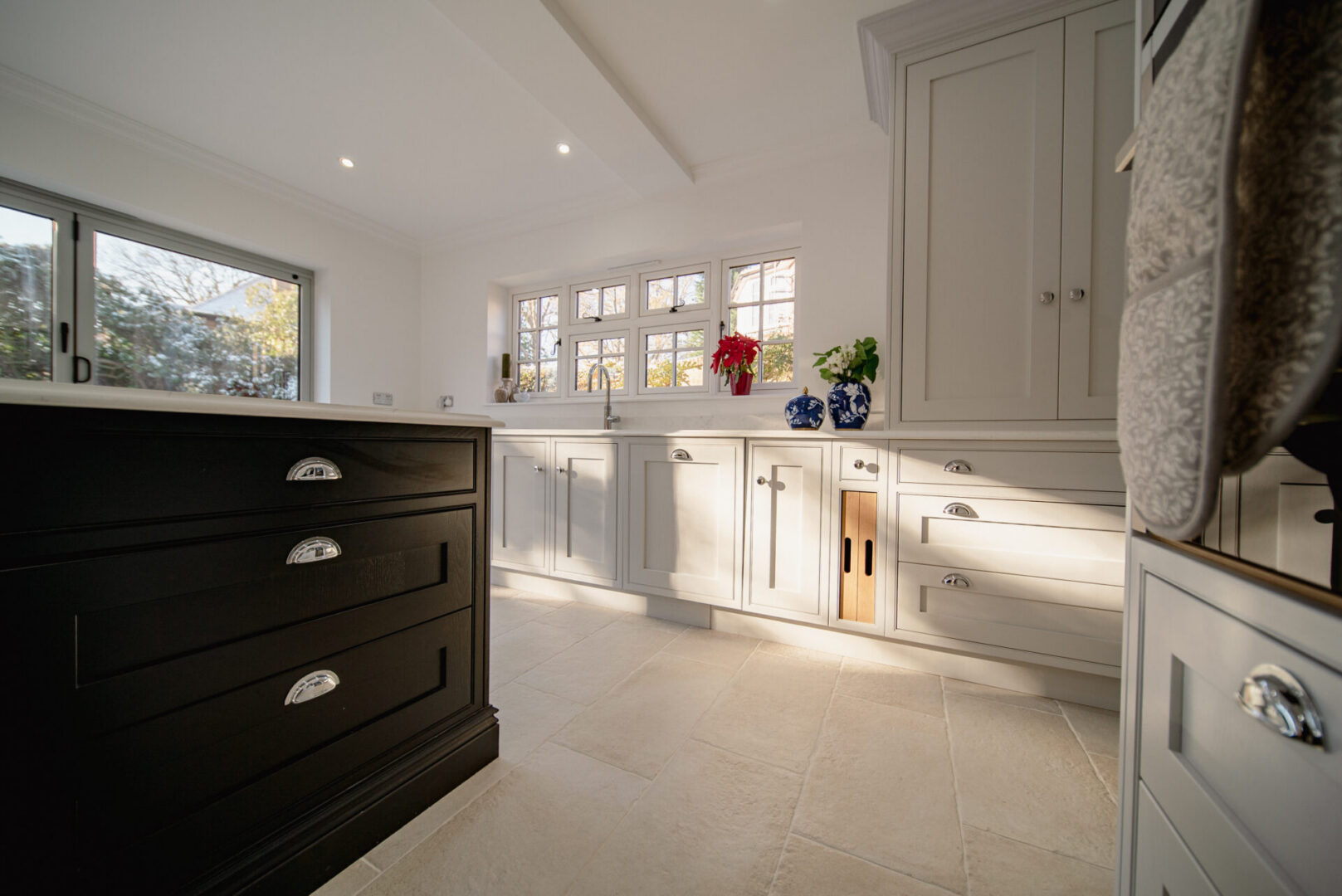 Kitchen with white cabinets and black drawers, a platform with drawers and cupboards, vases with flowers, a wash basin