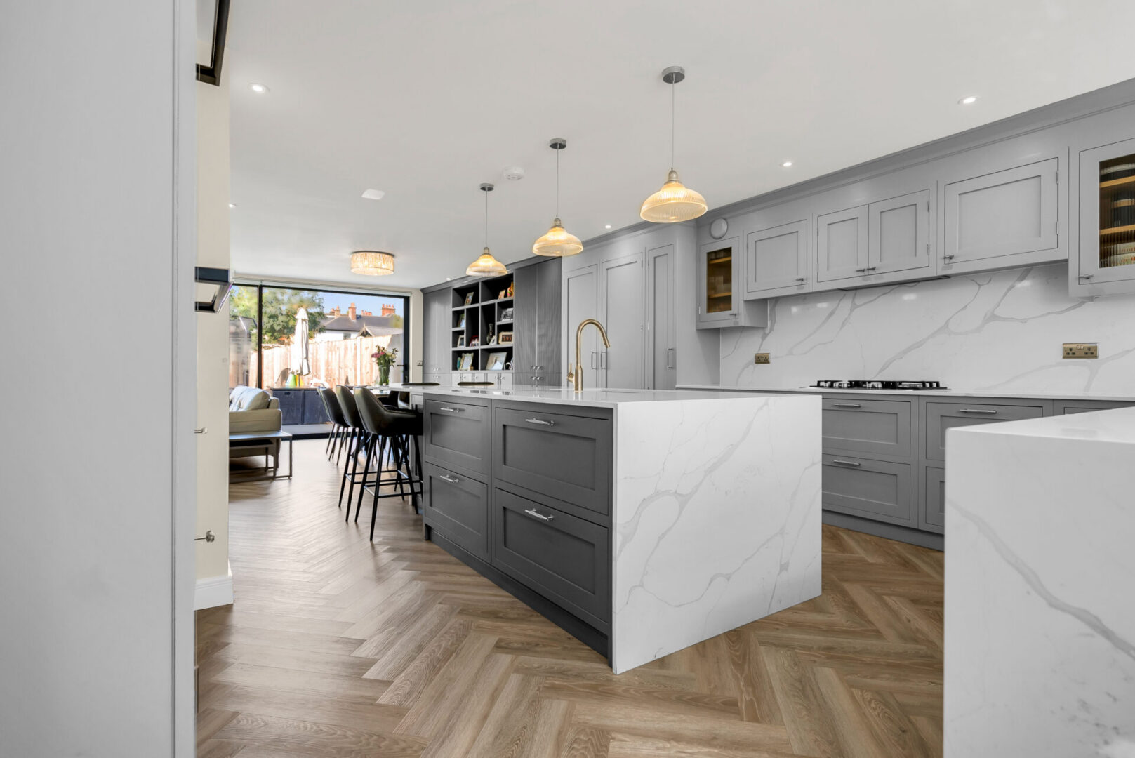 Kitchen with a large island in the middle of it, featuring a sink, tap, stove, cupboards