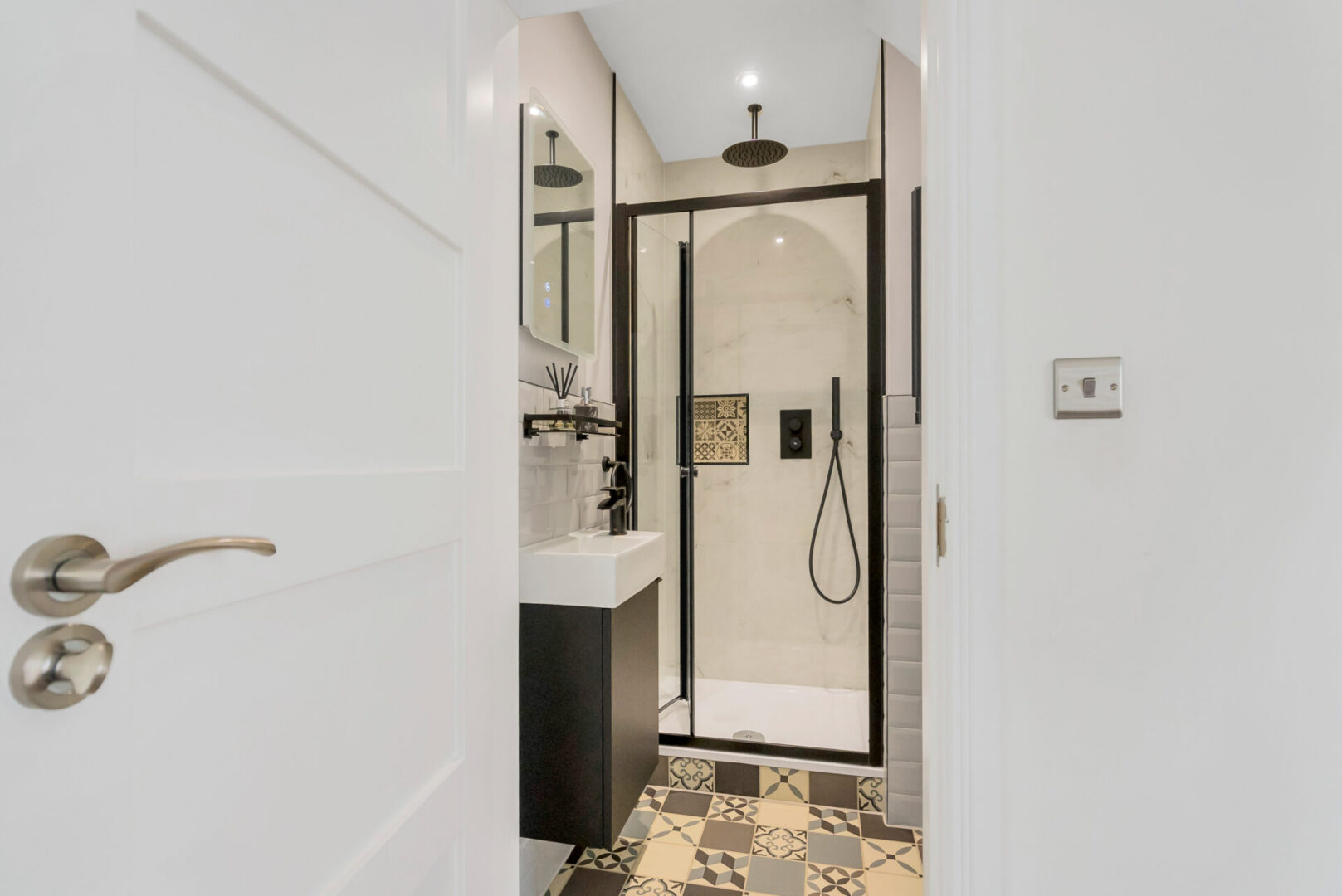 Bathroom with a door with a handle, a wash basin with a tap, a mirror on the wall