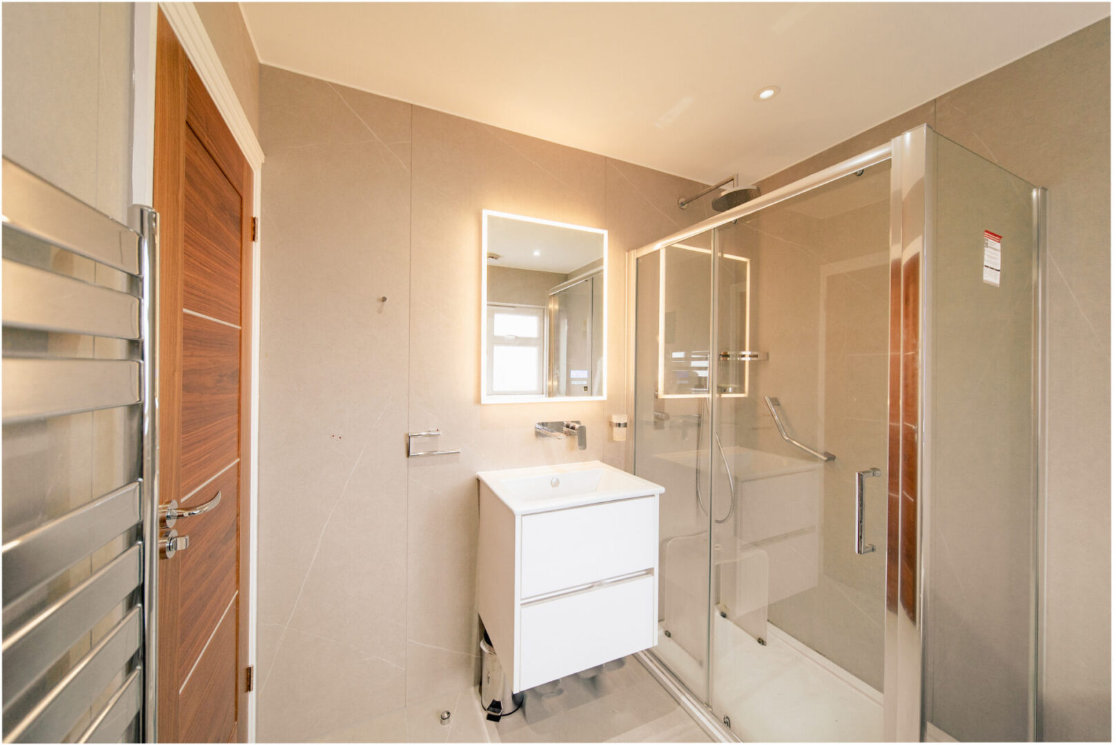 Bathroom with a sink, mirror, shower, glass door, electric lights to the roof, and a towel rack